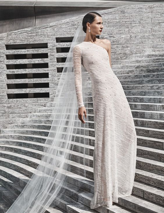 a unique textural semi fitting wedding dress with one long sleeve and rhinestones is a bold idea for those who want to impress