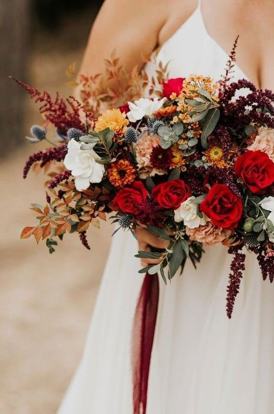 a vibrant fall wedding bouquet of deep red, white, burgundy, rust blooms, greenery, bold fall foliage and thistles is amazing