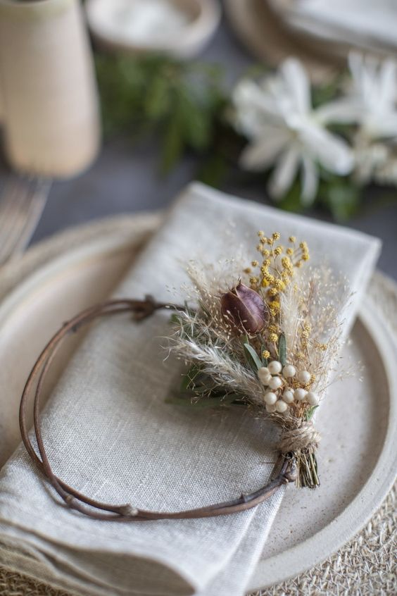 a vine napkin ring with some dried blooms is a great idea for a fall wedding, whether it's a boho one or not