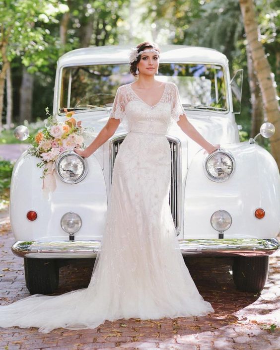 a vintage art deco embellished wedding dress with a -neckline and short sleeves, a train and an embellished headband, statement earrings