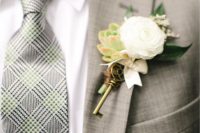 a vintage boutonniere of a white bloom, a succulent, some leaves, white ribbon and a vintage key is a gorgrous idea for a vintage wedding