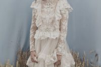 a vintage-inspired A-line champagne wedding dress with a turtleneck, long sleeves, ruffles and a tiered skirt plus a veil