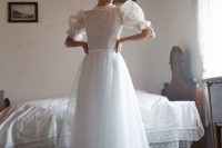 a vintage-inspired A-line tea-length wedding dress with a lace bodice, puff sleeves, a pleated skirt, floral shoes and a floral headband