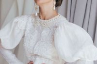 a vintage-inspired A-line wedding dress with a boho lace bodice and a crochet collar, puff sleeves, pearl buttons and statement pear earrings