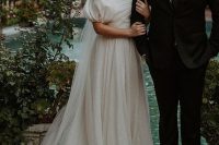 a vintage-inspired A-line wedding dress with a draped bodice and a pleated skirt with a train, puff sleeves, a veil for a refined wedding