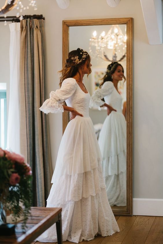 a vintage-inspired and boho bridal look with a lace A-line wedding dress with a square neckline, puff and bell sleeves, a tiered ruffle skirt and a train