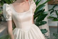 a vintage princess-style wedding ballgown with a pearly square neckline, short puff sleeves, an embellished headband and a pleated full skirt