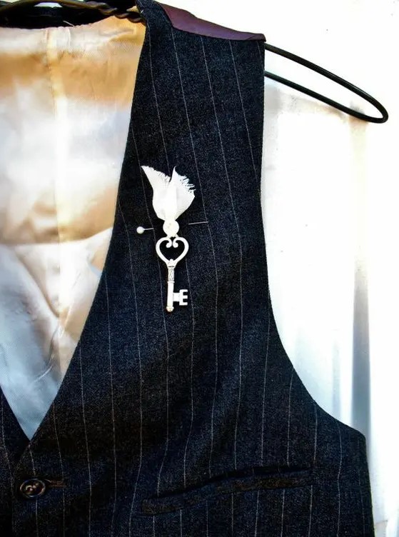 a whimsy boutonniere of a vintage key and a bead in a fabric cover looks vintage and fairy tale like at the same time