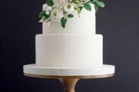 a white and polka dot wedding cake decorated with sugar blooms and leaves is a lovely wedding dessert