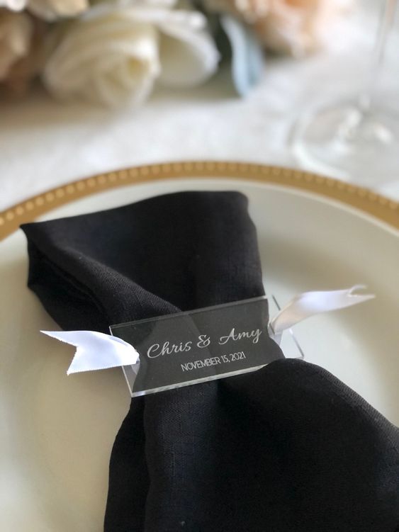 a white ribbon napkin ring topped with an acrylic card with the couple's names and date for a super modern wedding