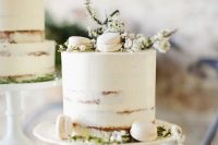 a white semi-naked wedding cake topped with blooms and white macarons is a gorgeous idea for a spring wedding
