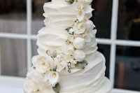 a white textural wedding cake with white blooms and leaves is a refined and chic idea