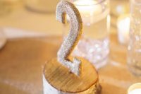 a wooden slice with a glitter table number is a nice idea for a rustic fall or winter wedding