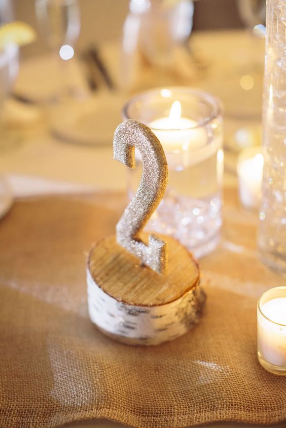 a wooden slice with a glitter table number is a nice idea for a rustic fall or winter wedding
