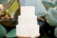 an all-white wedding cake decorated with macrame is great for desert or boho weddings