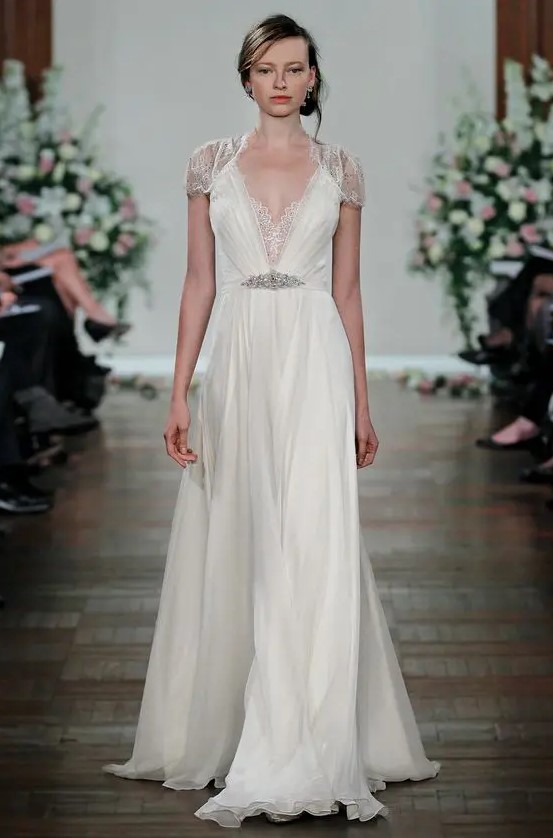 an art deco wedding dress with lace cap sleeves, a deep V neckline with lace detailing and an embellished belt