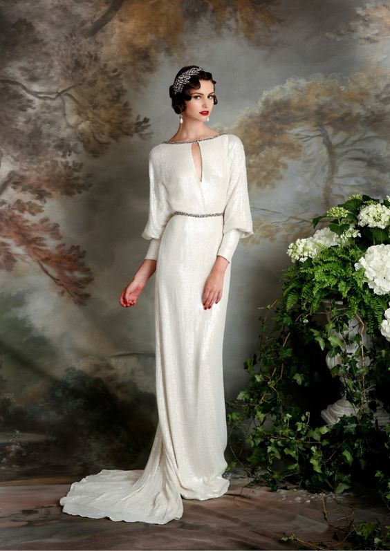 an art deco white sequin wedding dress with a high and cutout neckline, vintage sleeves, a train, an embellished headpiece and pearl earrings