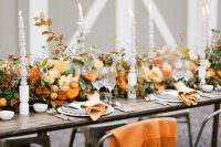 an elegant orange wedding tablescape with a super lush floral table runner, lovely tall candles and orange blankets for cuddling