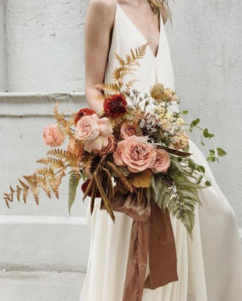 an organic super dimensional pastel wedding bouquet with blush and rust blooms, gold and green leaves and some herbs for a delicate feel
