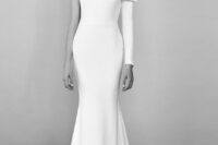 an understated glam one shoulder wedding dress with a long button sleeve, a large bow on the shoulder and a train