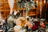 beautiful and lush fall rustic wedding decor with pumpkins, greenery, pink and deer red blooms and candles in gold candleholders