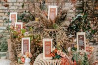 beautiful outdoor fall wedding decor with rattan tables and ottomans, fall foliage and blooms, pampas grass and signage