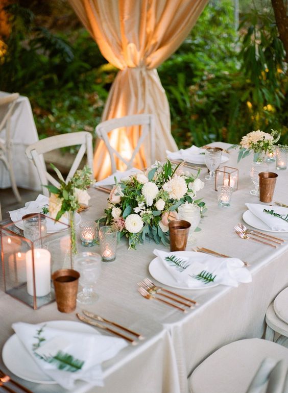 copper glasses and cutlery, copper candle lanterns and neutral blooms create a chic tablescape