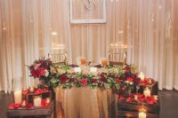 deep red petals and blooms accent the rustic glam sweetheart table and add a touch of bold color