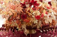 display burgundy escort cards around a gold vase with bright blooms, berries and white leaves for the fall