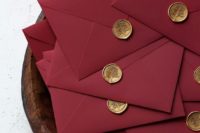 elegant burgundy envelopes with gold seals are amazing for a bold fall or winter wedding