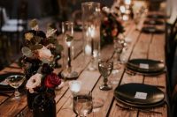 a Halloween wedding table with black plates and cutlery, black candles, deep purple, red and blush blooms