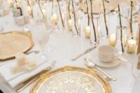 a beautiful and refined white and gold wedding tablescape with white rose cluster centerpieces, printed gold chargers, elegant cutlery and candles