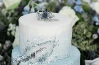 a beautiful ombre ice blue winter wedding cake with crystals and a thistle on top the cake is lovely