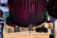 a beautiful purple ombre wedding cake with chocolate drip, fresh berries and blooms is stylish for Halloween