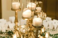 a beautiful wedding decoration of chic gilded candleholders, pillar candles, greenery and escort cards is a gorgeous idea