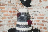 a black lace and white wedding cake with twigs, burgundy blooms and a faux blackbird on top is ideal for Halloween