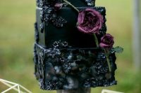 a black square wedding cake with sugar blooms, purple blooms, figs and berries is a stylish Halloween idea