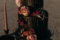 a black wedding cake with black drip, pastel blooms, leaves and berries for a Halloween wedding