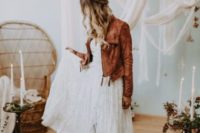 a boho bride in a lace dress and a brown leather jacket with tassels that adds color to the look