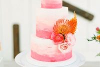 a bright ombre pink wedding cake with pink, red and orange blooms is a lovely idea for a summer or a tropical wedding