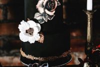 a chic black wedding cake with white and tan sugar blooms and gold leaves plus gold glitter for Halloween