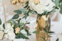 a chic modern wedding centerpiece of gold and white faceted vases, himmeli, white blooms and greenery