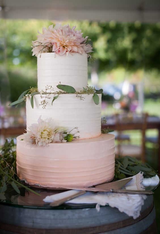 a delicate ombre pink wedding cake decorated with greenery and blush blooms is a lovely idea for a spring or summer wedding with a rustic feel