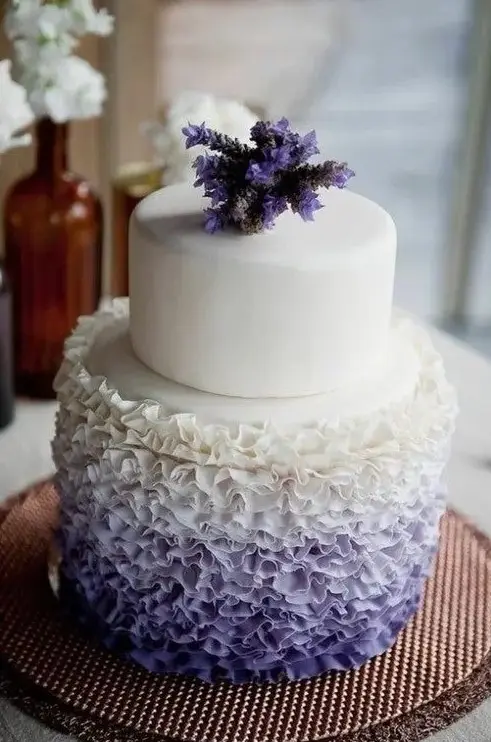 a fancy wedding cake with a white and ombre white to purple ruffle tier and with purple blooms on top is an amazing idea to rock