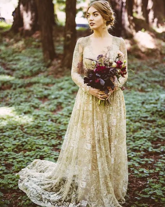 a gold wedding dress with white lace appliques, with a deep neckline and long sleeves for a dramatic look