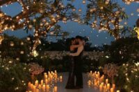 a gorgeous destination wedding ceremony space lit up with candleholders on the floor and hanging on the tree branches