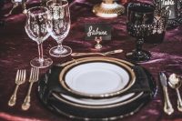 a gothic Halloween wedding tablescape with a purple tablecloth, gold touches, a bowl with a skull and blooms