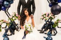 a hexagon wedding arch decorated with black, midnight blue and slate blue balloons and blooms