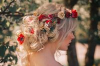 a messy and loose low updo with lots of waves and twists, bold red, pink and neutral blooms tucked in will work for both summer or fall wedding
