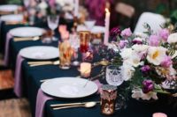 a midnight blue tablecloth loks very chic with purple napkins and purple and pink blooms